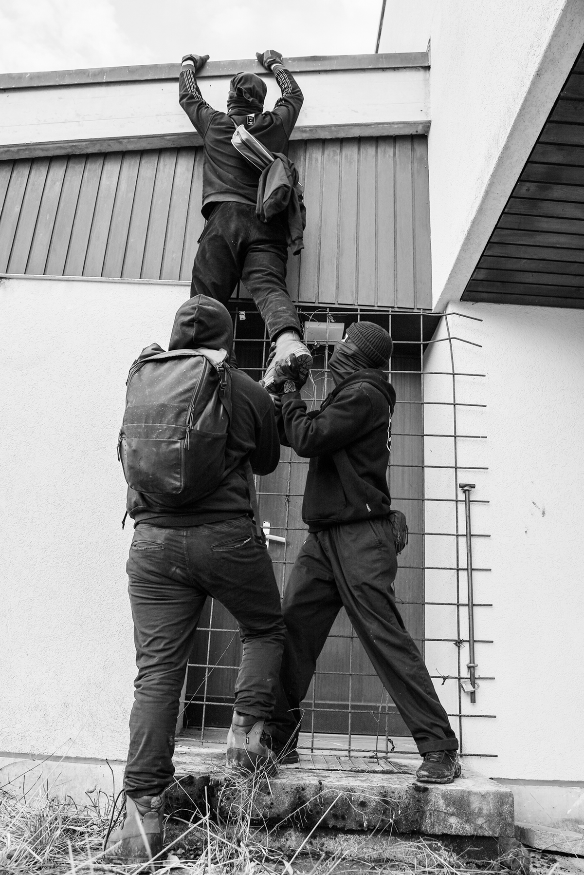 Grayscale stock photograph of people climbing a fence